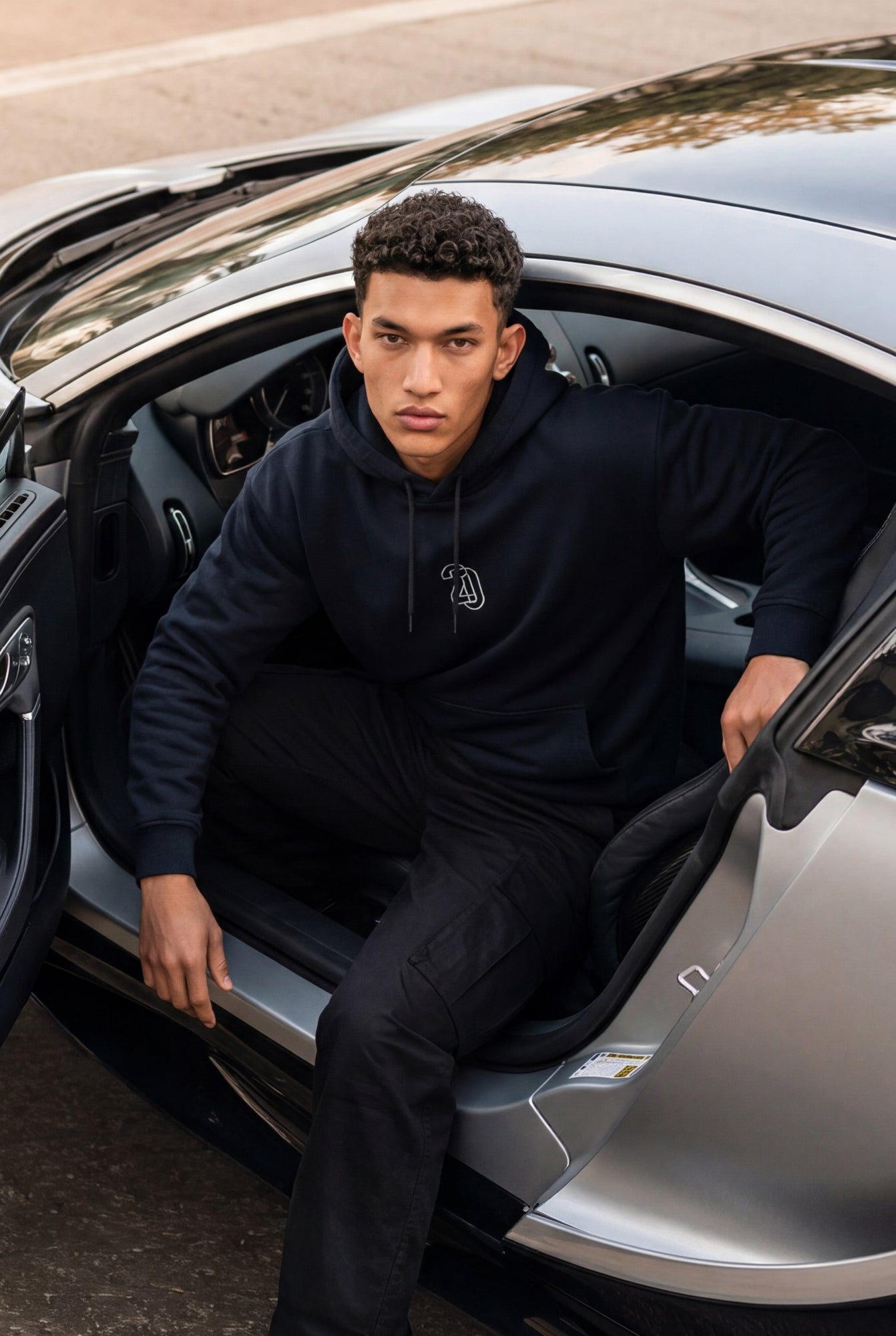 Person in a blue hoodie sitting inside a car